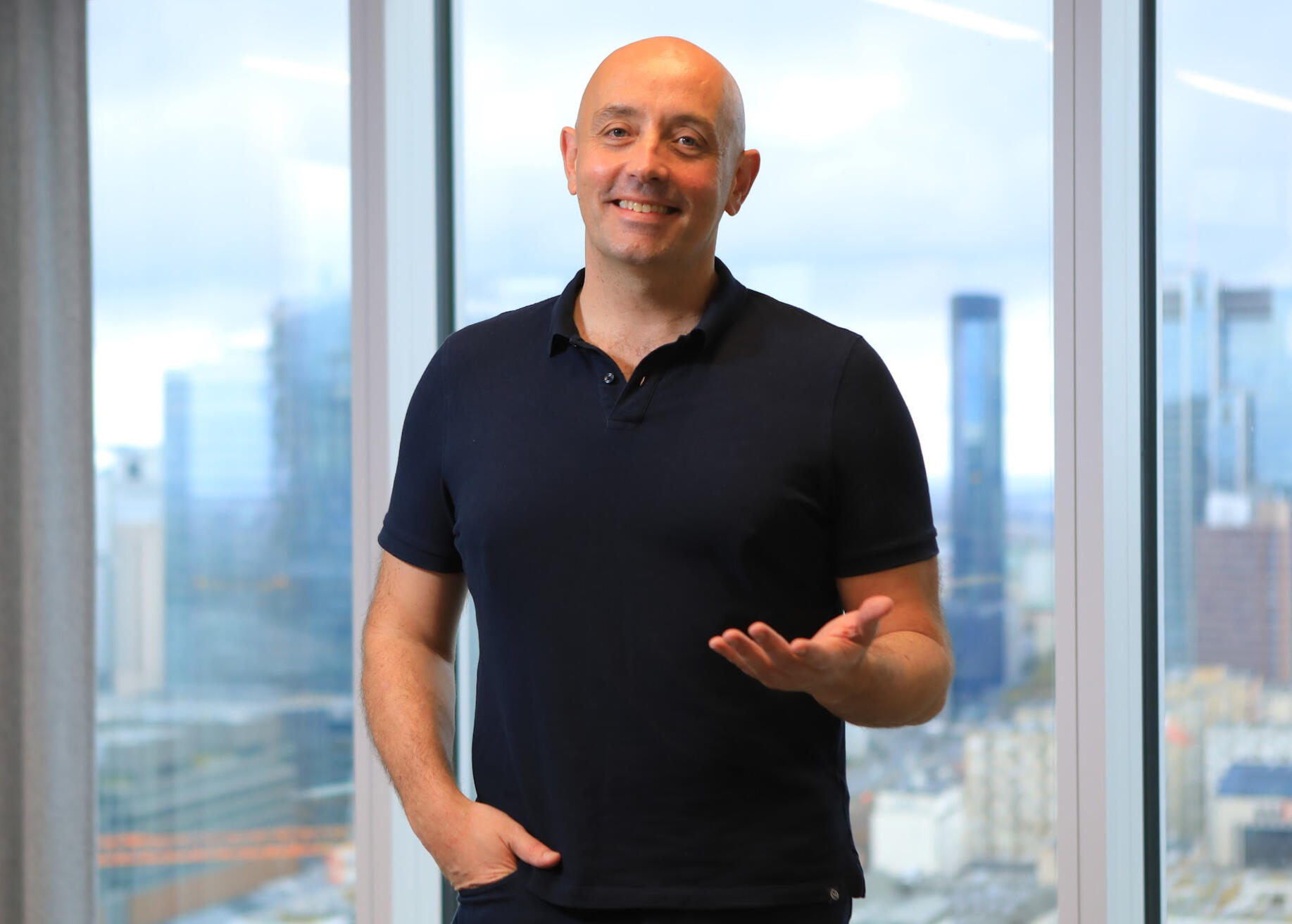 Simon McDermott standing by a window above the city skyline